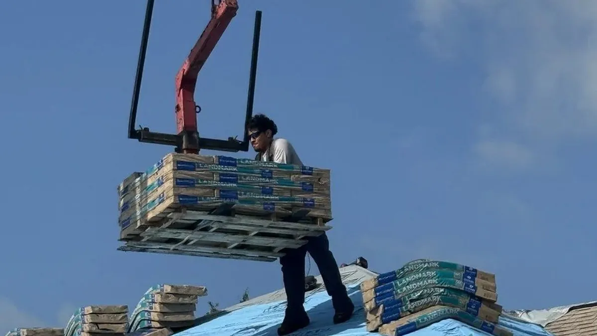 Roofer guiding a crane-lifted pallet of shingle bundles onto a dried-in roof deck in The Villages, Florida